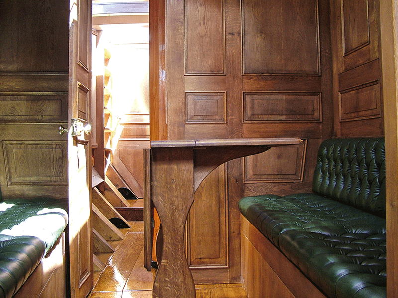 Emménagement intérieur d'Integrity : table en chêne et banquette en cuir vert capitonné.