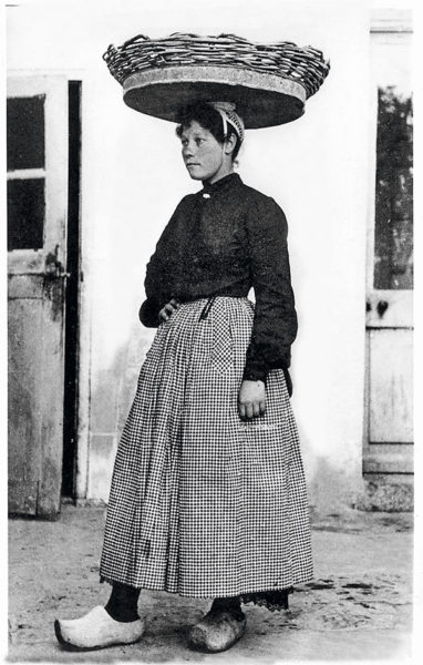 Femme portant un panier de sardines sur la tête.