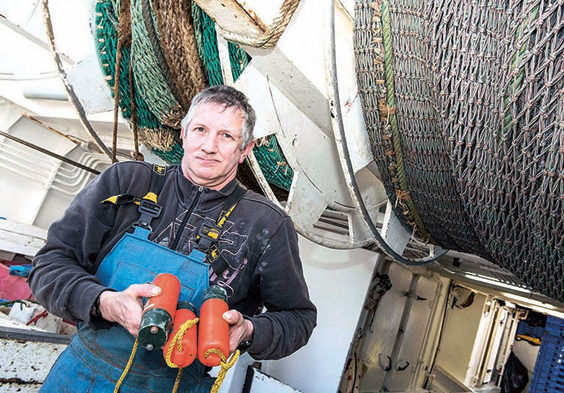 À bord du Carmalia, chalutier pélagique lorientais de 17,50 mètres, travaillant en bœuf, un matelot présente les pingers, répulsifs acoustiques à dauphins, qui seront installés à l’entrée du chalut.