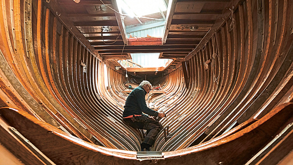 Un homme rénovant la charpente du bateau