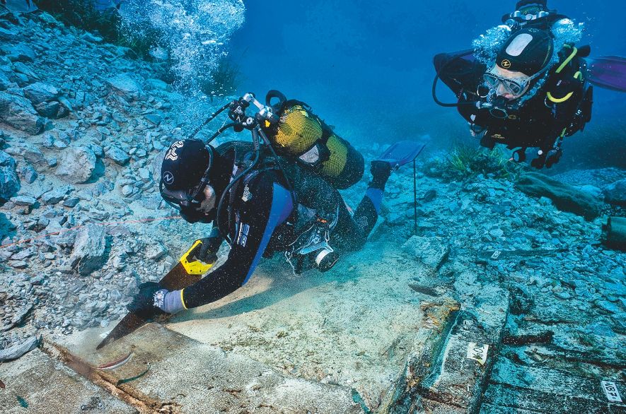 Deux plongeurs en mer découpant un bout de l'épave.