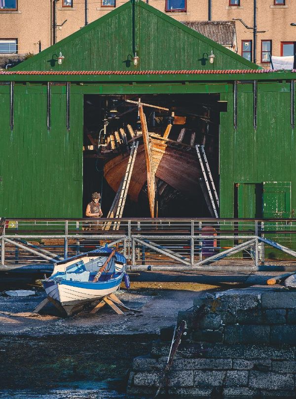 Vue en entière de l'entrepôt vert où se trouve le bateau, en travaux.