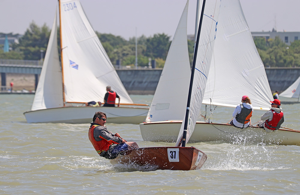 Les 1er et 2 juillet derniers, La Rochelle a accueilli les épreuves du trophée Michel Rouillé. Dans le sillage du 420, on reconnaît un Moth Europe (à gauche) et un Zef (à droite). En second rideau, le Dinghy 12 Lord Jim et, avec sa voile jaune, une réplique de houari nantais, construit en 1999 par Didier Léveillé, l’Atypique Houari de Montretraict.